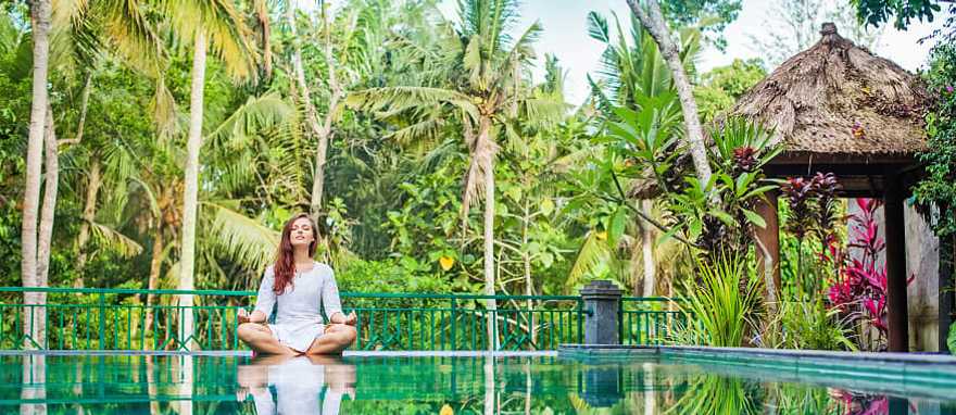Bali, Indonesia Woman meditating poolside at luxury resort in Bali