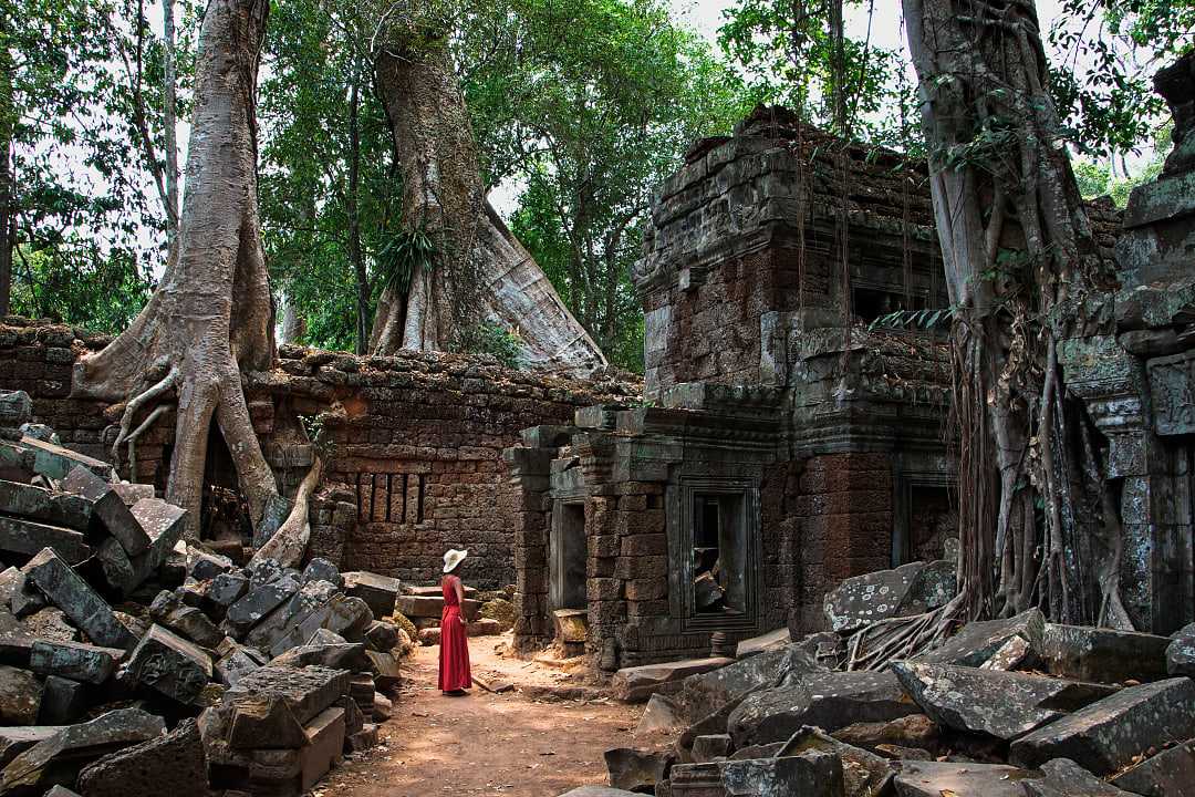 Woman in a red dress at Ta Prohm Temple ruins in Siem Reap, Cambodia