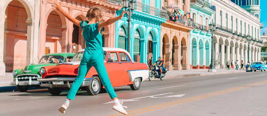 Girl in the street with vintage classic American car in old Havana, Cuba
