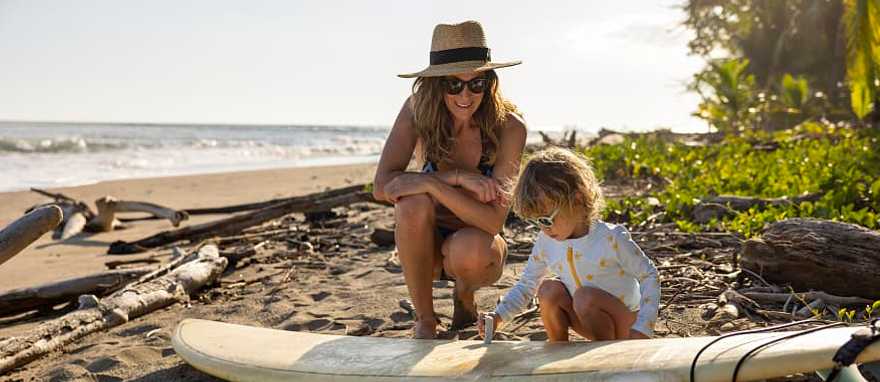 A young girl learning how to wax a surf board from her mother in Costa Rica A young girl learning how to wax a surf board from her mother in Costa Rica