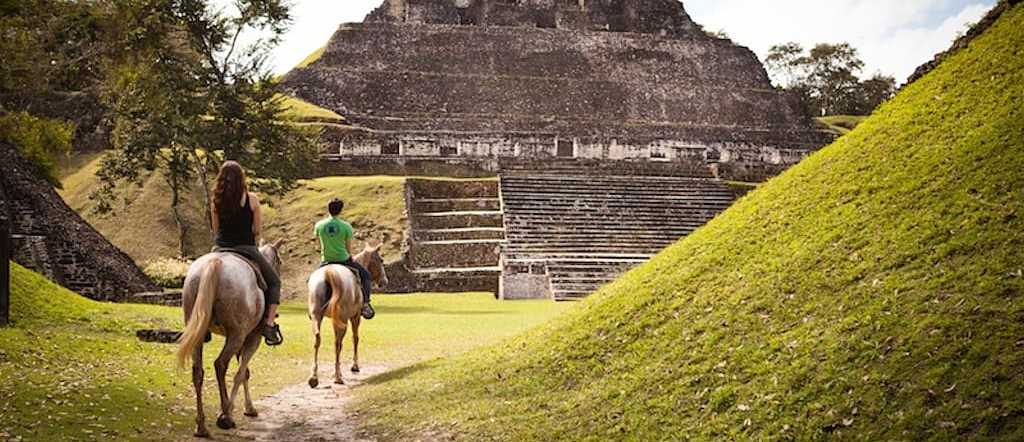 Couple horseback riding to the ancient Maya ruins of Xunantunich in Cayo District, Belize