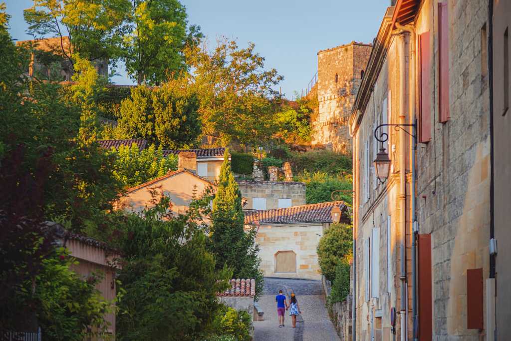 A couple hold hands strolling through the romantic village of Saint-Émilion in Bordeaux, France