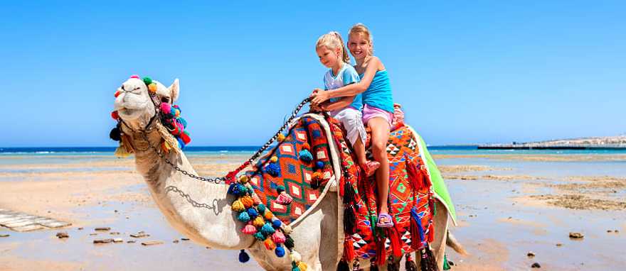 Sisters riding camel on the beach in Egypt