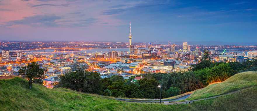 The Sky Tower in Auckland, New Zealand Auckland cityscape at dusk viewed from Mount Eden grassy slopes.