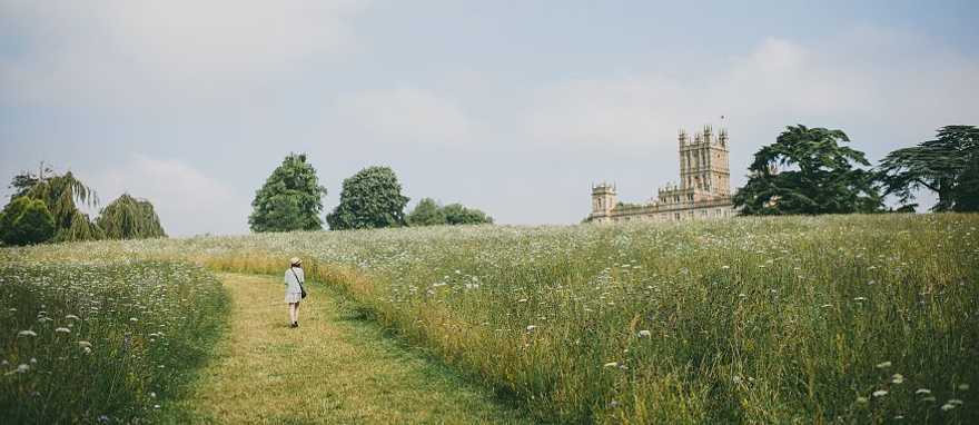 Highclere Castle in Hampshire, England. Visitor walking toward Highclere Castle through a wildflower field in Hampshire, England
