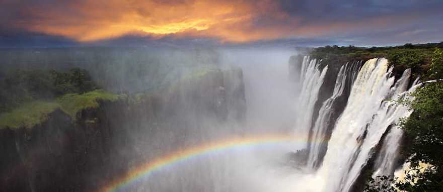 Gorgeous view of Victoria Falls at sunset with a rainbow forming in the mist, Zambia, Africa Gorgeous view of Victoria Falls at sunset with a rainbow forming in the mist, Zambia, Africa