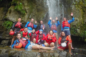 Zicasso staff under a waterfall, waving