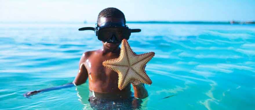 Belize Young boy shows off a starfish he found while snorkeling in Belize
