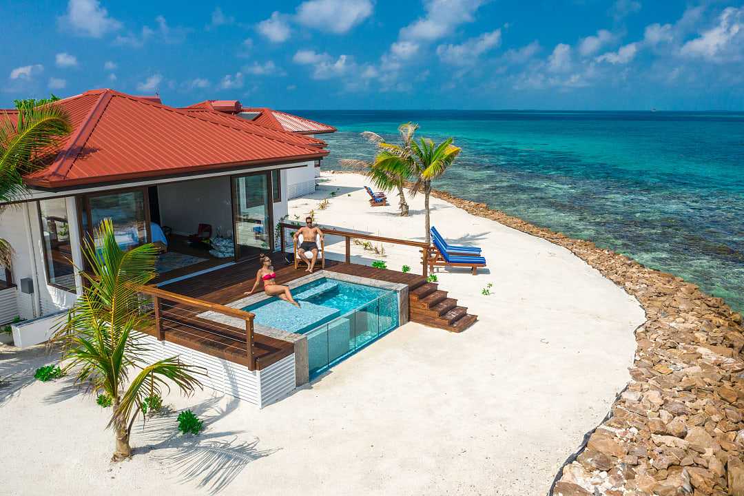 Couple at a luxury beachfront villa with a private pool, ocean view, and palm trees in Belzie